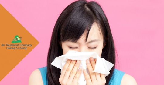 woman blowing her nose in front of pink background