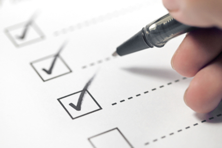 Hand holding black pen checking boxes.
