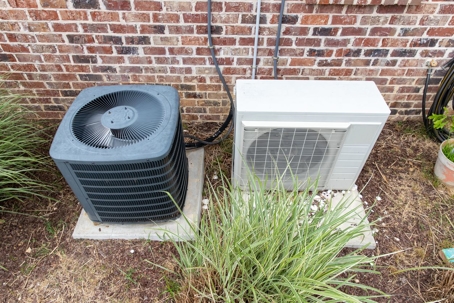 Regular home HVAC air conditioner system and mini-split next to each other.