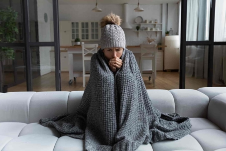 A woman shivering under a blanket