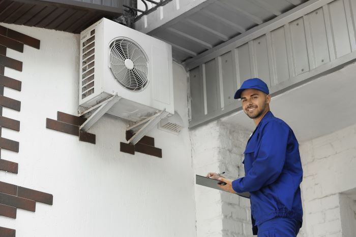 Technician standing with a clipboard near outdoor air conditioner